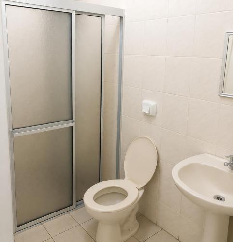 a bathroom with a shower and a toilet and a sink at Hotel D'Italia in Arroio do Sal