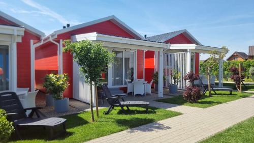 a row of red houses with chairs and tables at MORZA SZUM basen z podgrzewaną wodą, boisko, rowery in Sarbinowo