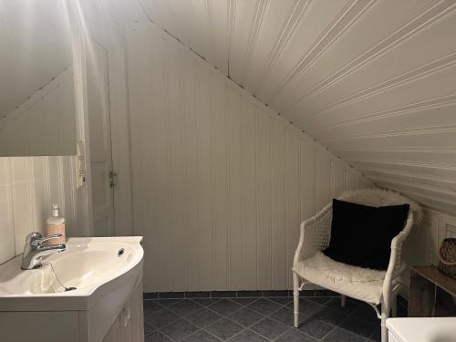 a bathroom with a sink and a chair with a mirror at Yttermoveien in Narvik