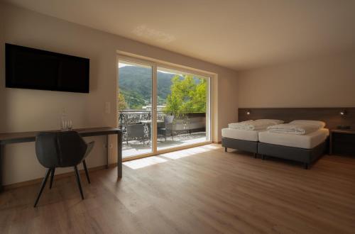 a bedroom with two beds and a large window at Hotel Harpf in Bressanone
