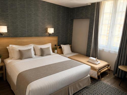 a hotel room with a large bed and a window at Le Grand Hôtel de Mayenne - Logis hôtels restaurant in Mayenne