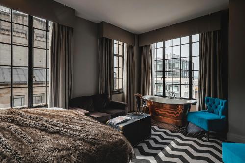 a bedroom with a bed and a chair and windows at The Rex - formerly Hotel Gotham in Manchester