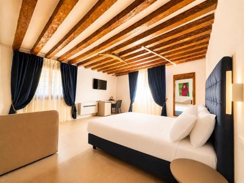 a bedroom with a large white bed and blue curtains at Casanova Hideaway in Venice