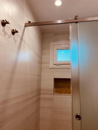 a shower with a window in a bathroom at Alkisti's seaside apartments in Pythagoreio