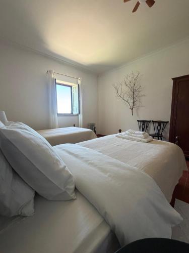 a bedroom with two beds with white sheets and a window at Casa do Cardal in Casével