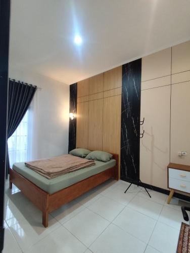 a bedroom with a bed with a wooden wall at Griya Alborz Dieng in Garung