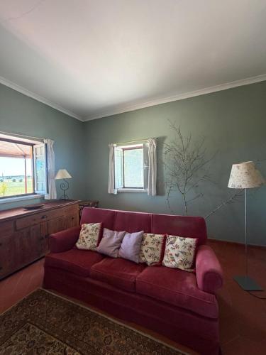 a living room with a red couch and a window at Casa do Cardal in Casével