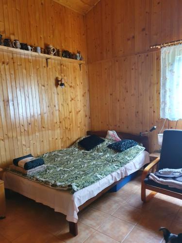 a bed in a room with a wooden wall at Domek letniskowy in Rogówko