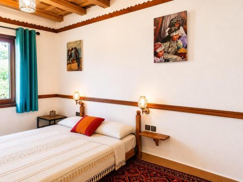 a bedroom with a bed and a painting on the wall at Auberge des peupliers Café Restaurant in Akhendachou nʼAït Ouffi