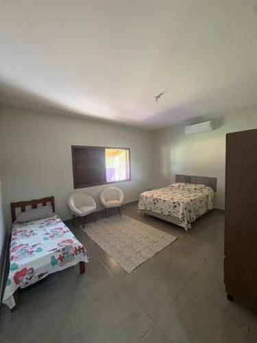 a bedroom with two beds and two chairs in it at Chácara do Cardoso in Três Marias