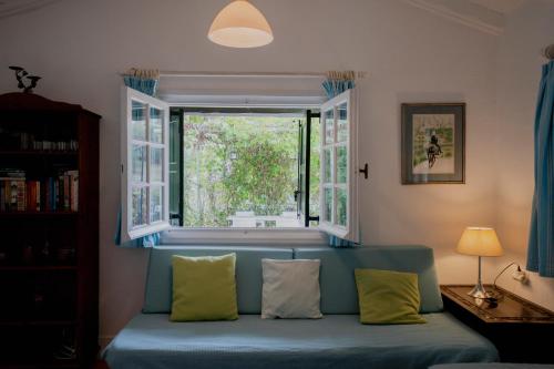 a blue couch in a living room with a window at Casa Lucia Green Cottage in Corfu