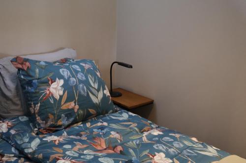 a bed with a blue blanket with flowers on it at B&B de Beurtvaart in Dokkum
