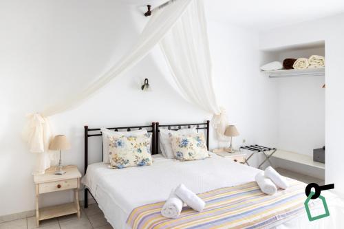 a bedroom with a bed with white sheets and pillows at Hotiday Santorini Seafront in Santorini