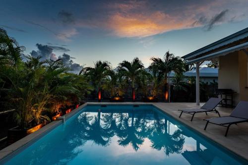 a swimming pool with two chairs next to a house at Villa Ti'Palm in Saint-François