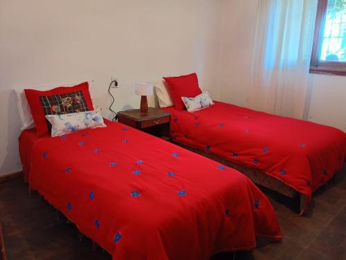 two beds in a room with red comforter at Casa JINDRA in Puerto Madryn