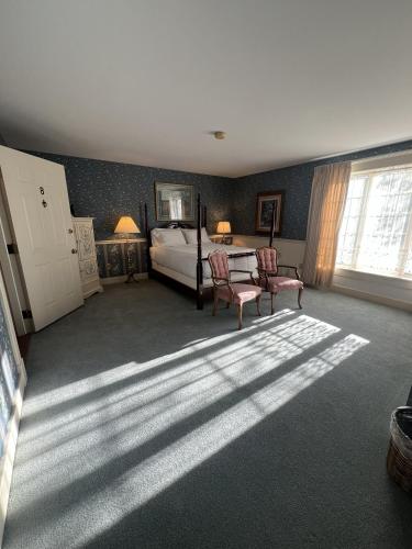a bedroom with a bed and two chairs and a window at Strawtown Inn & Events in Pella
