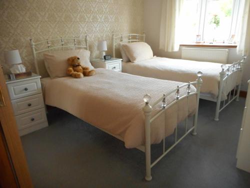 a teddy bear sitting on a bed in a bedroom at Dripshill Lodge in Severn Stoke