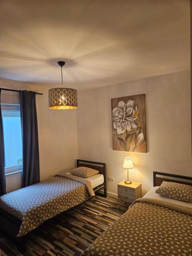 a bedroom with two beds and a chandelier at Apartment Rita in Mokošica