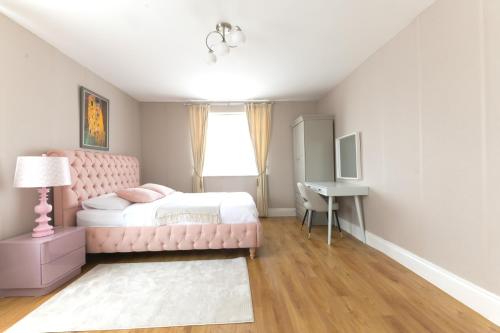 a bedroom with a pink bed and a desk at Katolondonhaus in Mitcham