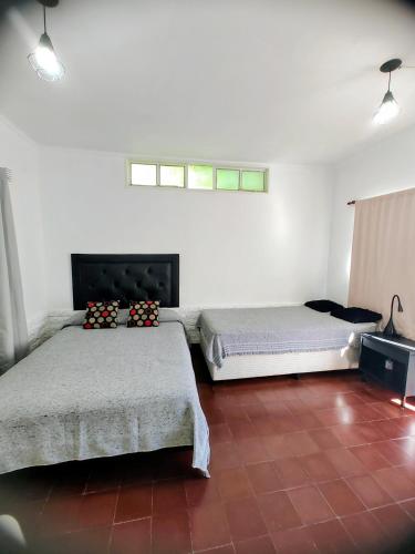 two beds in a room with a red tile floor at 866 Apart in San Fernando del Valle de Catamarca