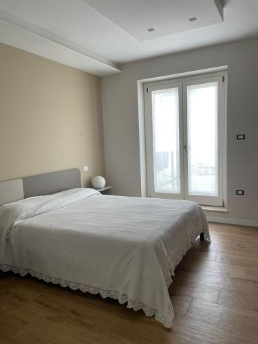 a white bedroom with a large bed and two windows at Villa Miranda in Ortona