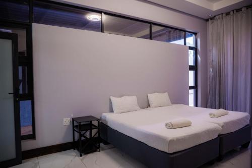a bedroom with a white bed with a large window at Oasis Apartment Suites in Ezulwini