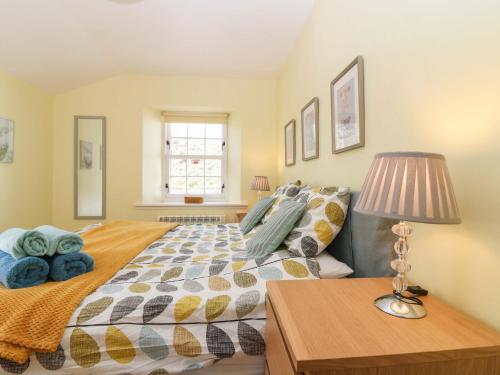 a bedroom with a bed and a table with a lamp at Lightkeepers Fold in Eyemouth