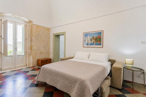 a white bedroom with a bed and a window at Villa Stone and Sea Escape by Apulia Accommodation in Cozze