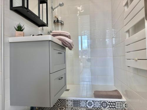 a white bathroom with a shower and a sink at Appartement Standing proche des Thermes in Vichy
