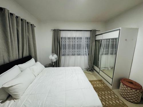 a bedroom with a large white bed and a window at Vantage Suite in Lilongwe