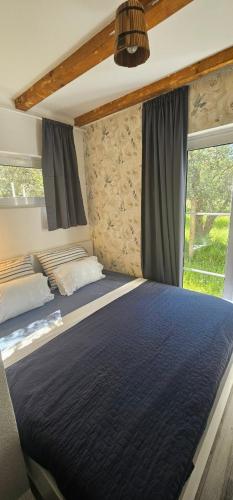 a bedroom with a large blue bed with a window at Sabina Olive bungalow in Ulcinj