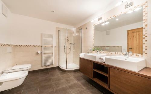 a bathroom with two sinks and a shower and a toilet at Residence Fischerhof in Tirolo