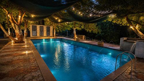 a swimming pool with lights in a backyard at night at The Wilds Villa Gir Jungle Stay with Swimming Pool in Sasan Gir