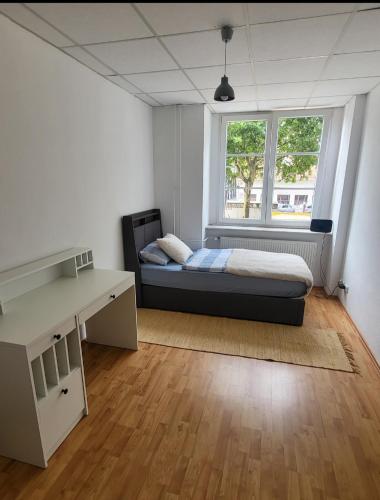 a bedroom with a bed and a desk and a window at Tolle Stadtwohnung in Darmstadt