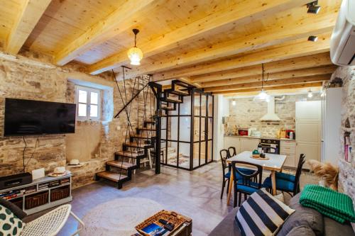 a living room with a stone wall and a spiral staircase at Mala House - Šolta Island in Grohote