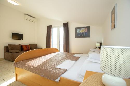 a bedroom with a large bed and a couch at Apartmani Liovic in Duće