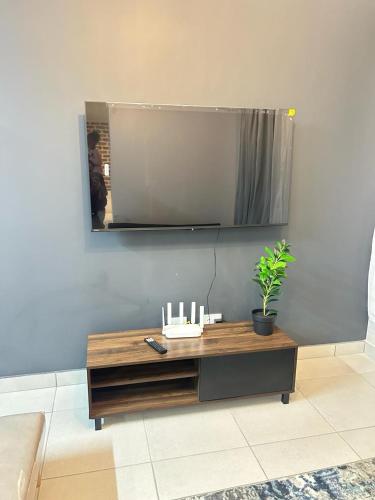 a living room with a table with a tv on the wall at Elisa's Haven in Matsulu
