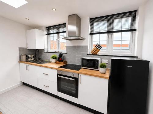 a kitchen with white cabinets and a black refrigerator at The Regent in Warrington