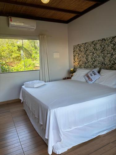 a bedroom with a large white bed with a window at Chalés Casa de Vidro in Alter do Chao