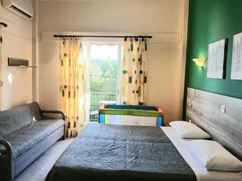 a bedroom with a bed and a couch and a window at Hermes in Agia Marina Aegina