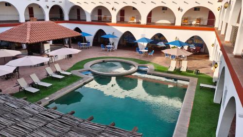 an indoor pool in a building with chairs and umbrellas at Hotel Hacienda Bugambilias La Paz in La Paz