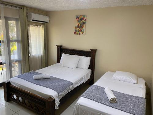 a bedroom with two beds with towels on them at Hotel Oasis Beach Club in Puntarenas