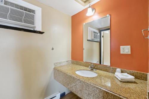 a bathroom with a sink and a mirror at Currys Motel by OYO Saginaw MI in Saginaw