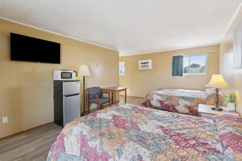 a hotel room with two beds and a flat screen tv at Currys Motel by OYO Saginaw MI in Saginaw