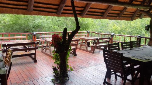 a deck with tables and benches and a vase of flowers at Jabula Kruger Safari Lodge in Marloth Park