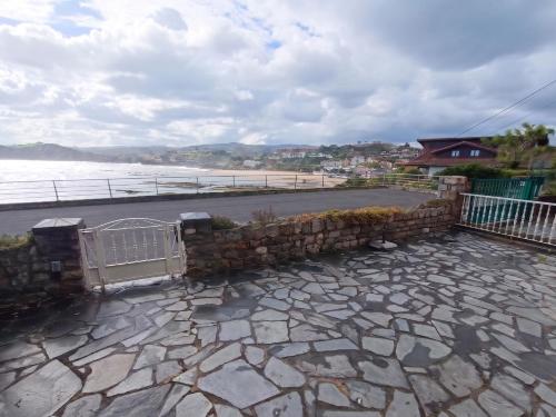 a stone retaining wall next to a beach at Casa del Muelle COMILLAS in Comillas