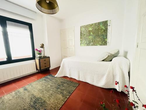 a white bedroom with a bed and a window at NEW - Casa Palamós - Charming historical home with patio, in the heart of the old town, 100m from beach in Palamós