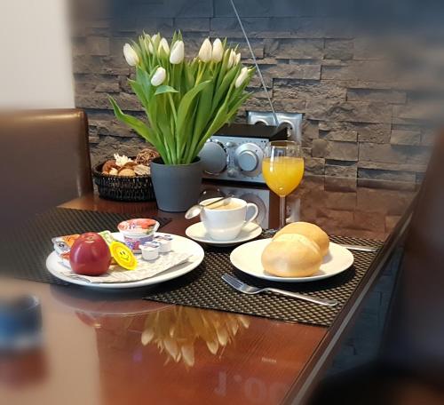 a table with plates of food and a glass of orange juice at Triumph Inn Pension in Rangsdorf