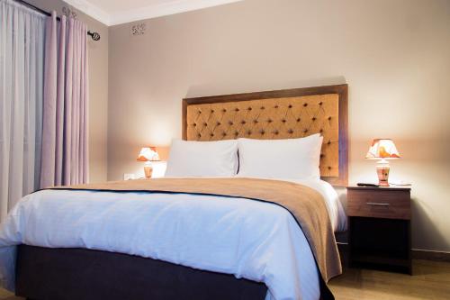 哈拉雷的住宿－撒瑞姆小屋酒店，一间卧室配有一张大床和木制床头板
