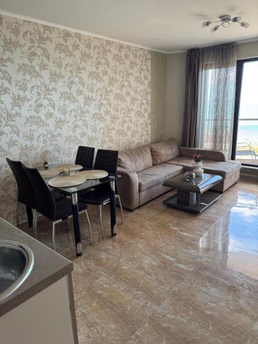 a living room with a couch and a table and chairs at Infinity Sea View Deluxe Apartment in Pomorie